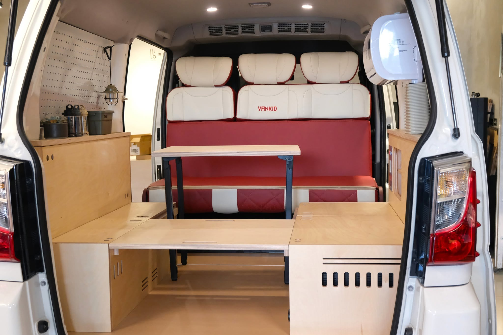 野孩子菱利 A180 車尾全景，紅白雙色座椅搭配樺木櫃體、桌面與洞洞板