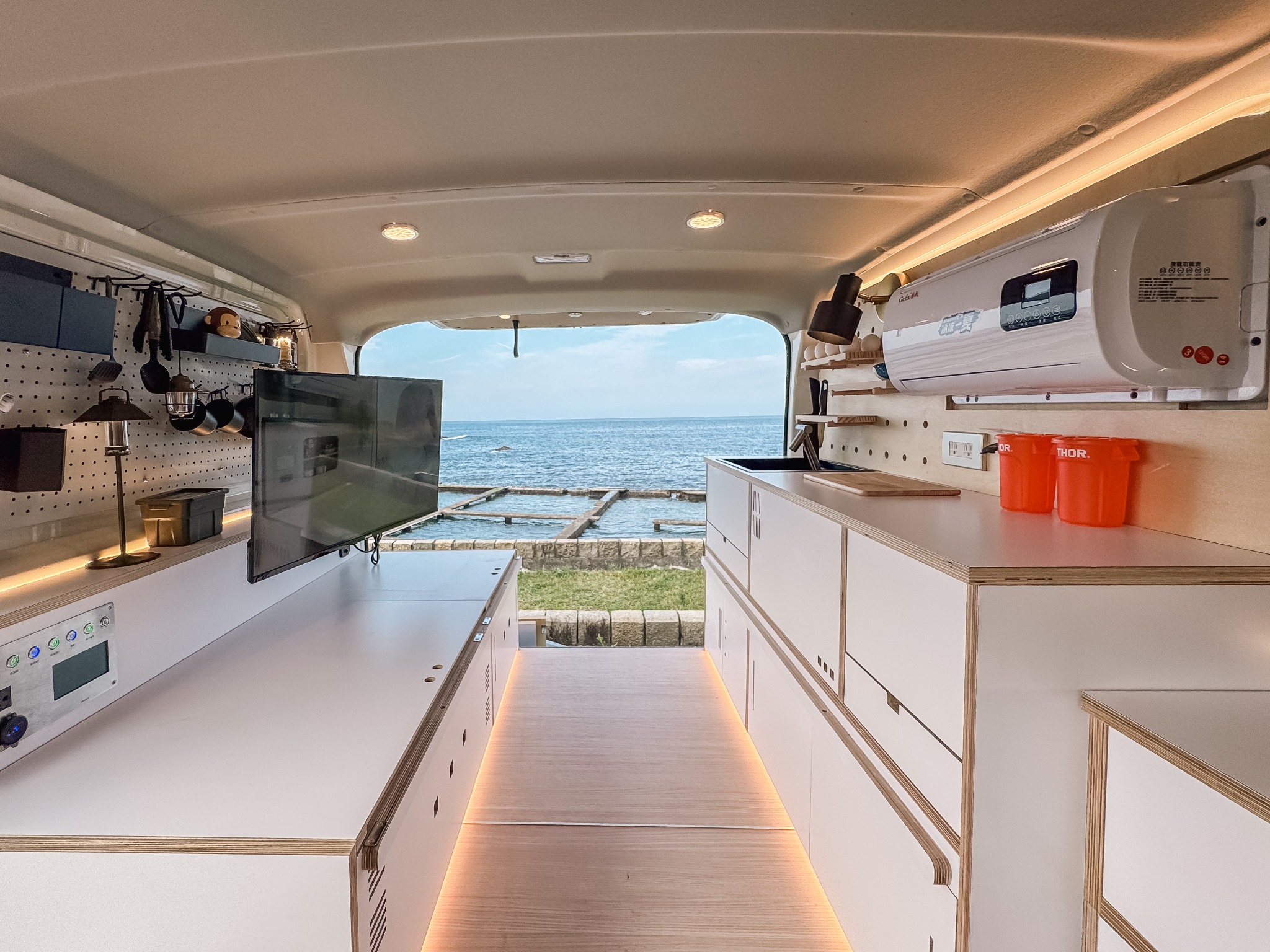 野孩子 Hiace 海力士車內廚房與兩側洞洞板,尾門外可見海景